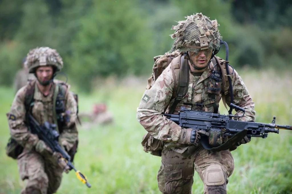 Two soldiers running while carrying weapons