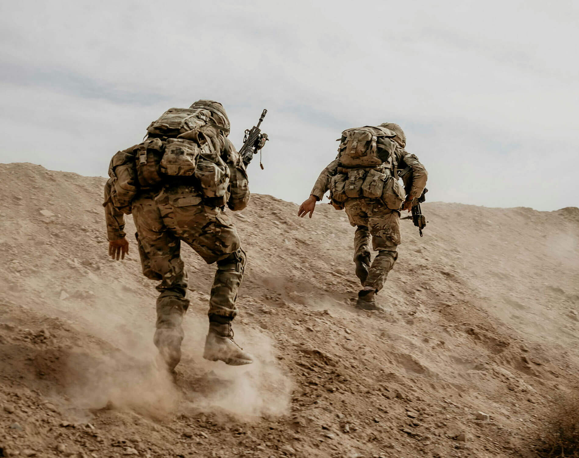 Two soldiers running up a sand hill